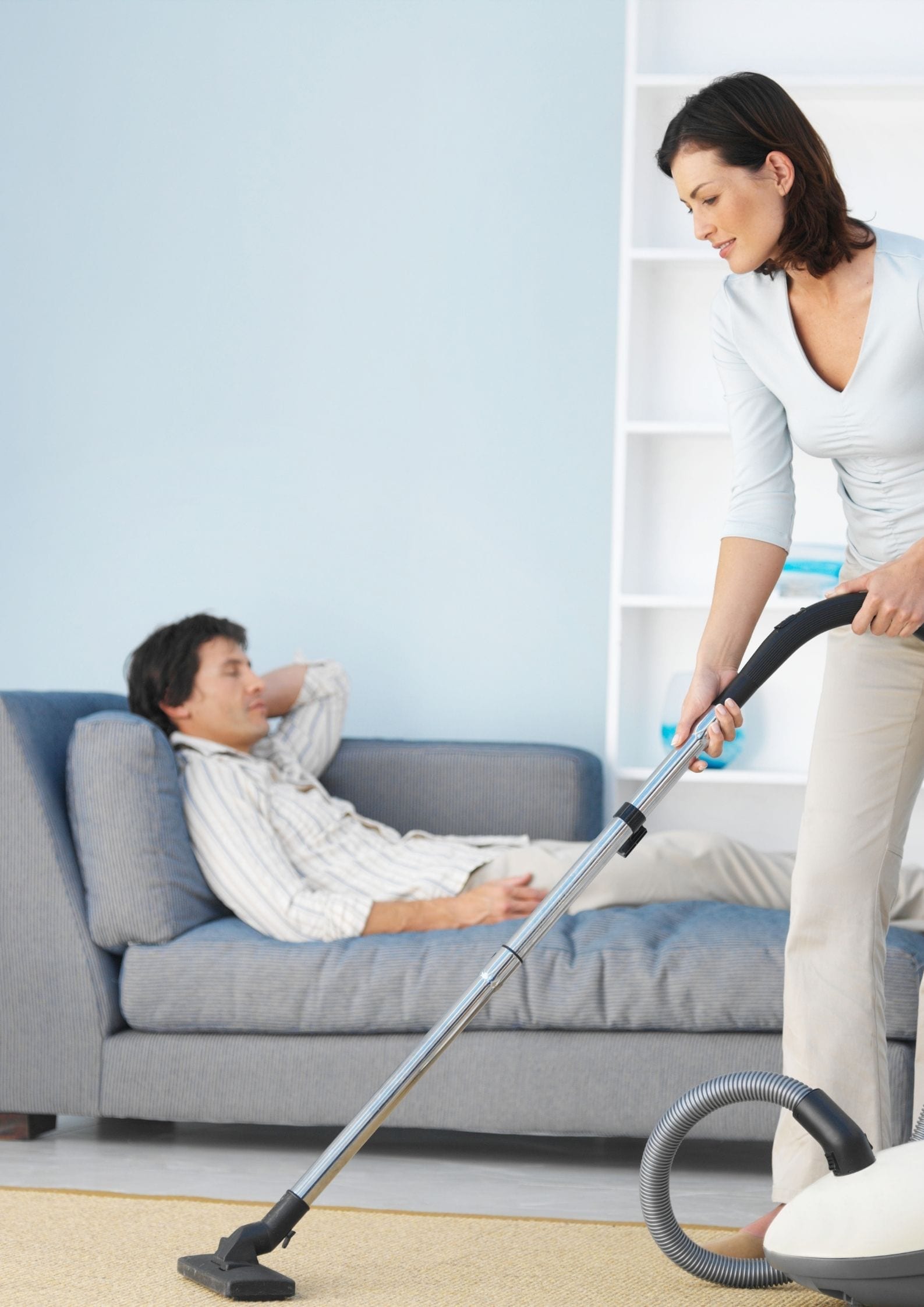 Man relaxes whilst woman irons