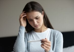 Woman looking sad holding a pregnancy test