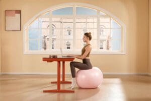 Can Exercise Make You Better at Your Job? The Surprising Career Benefits of Fitness 1 woman working on a laptop whilst sitting on a gym ball
